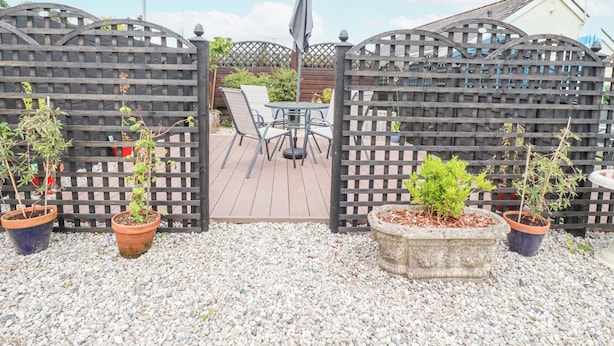 Un espace patio agrémenté d’une clôture en bois, d’une table avec des chaises et de plantes en pot.