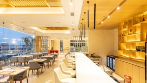 Un restaurante moderno con una barra alargada, varias mesas y sillas.