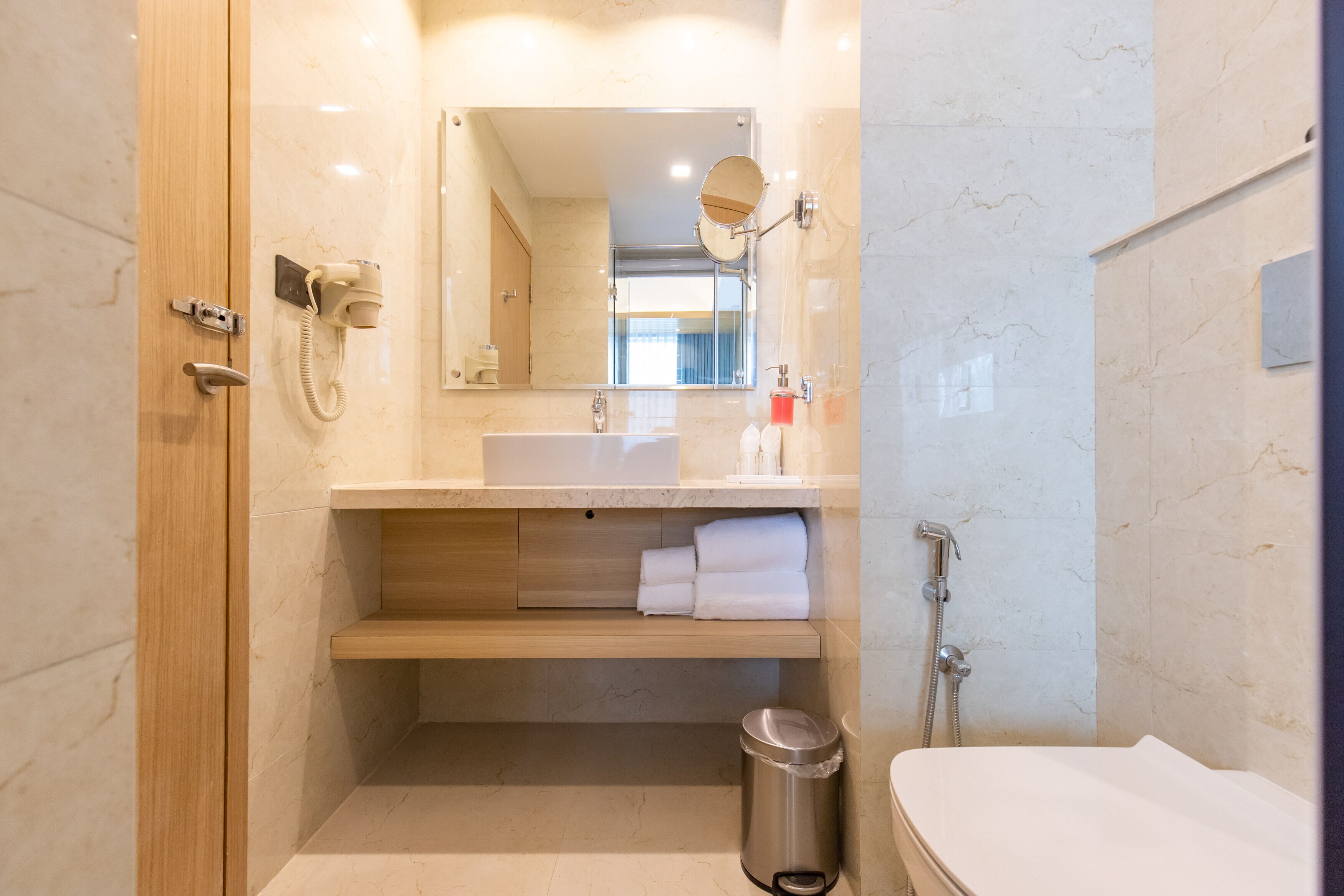A modern bathroom with a wooden vanity, a mirror, a sink, and a shower.