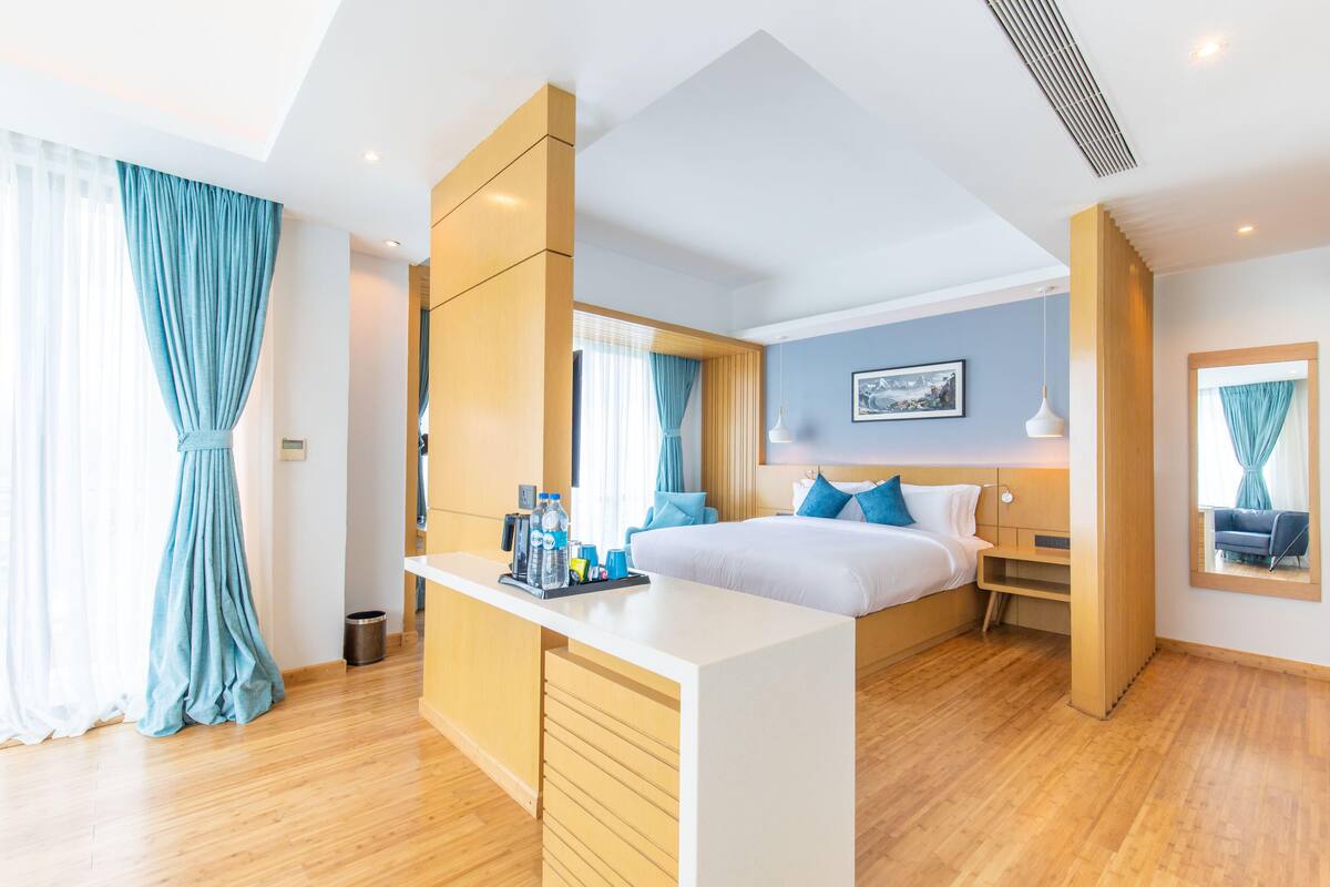 A modern hotel room with a large bed, a desk, and a mirror.