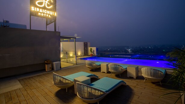 Terraza lounge del Hotel Siraichulli con piscina, sillones de descanso y vista a la ciudad al atardecer.