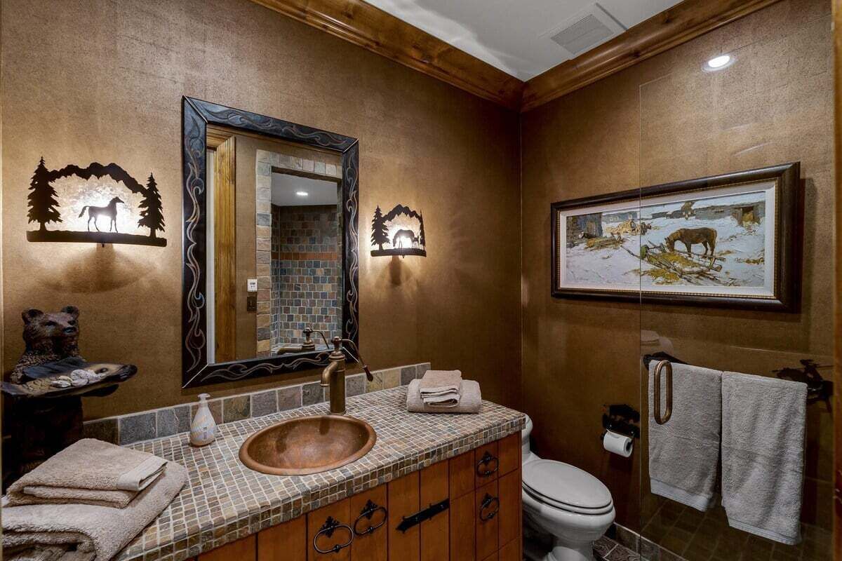 Un baño con tocador de madera, un lavabo, un espejo y un cuadro en la pared.
