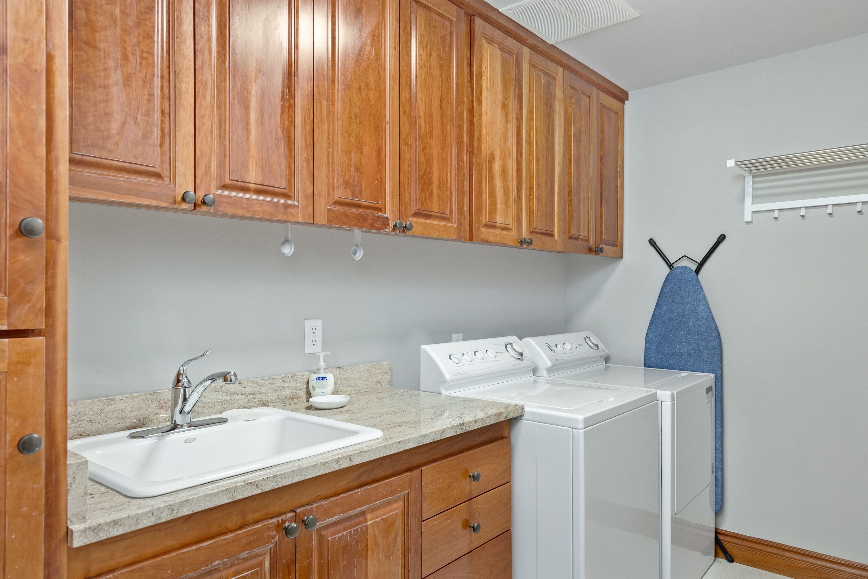 A kitchen with wooden cabinets, a sink, and a white washing machine.