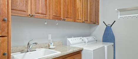 A kitchen with wooden cabinets, a sink, and a white washing machine.
