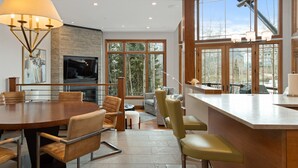 A modern kitchen with a large island, dining area with chairs, and a fireplace.