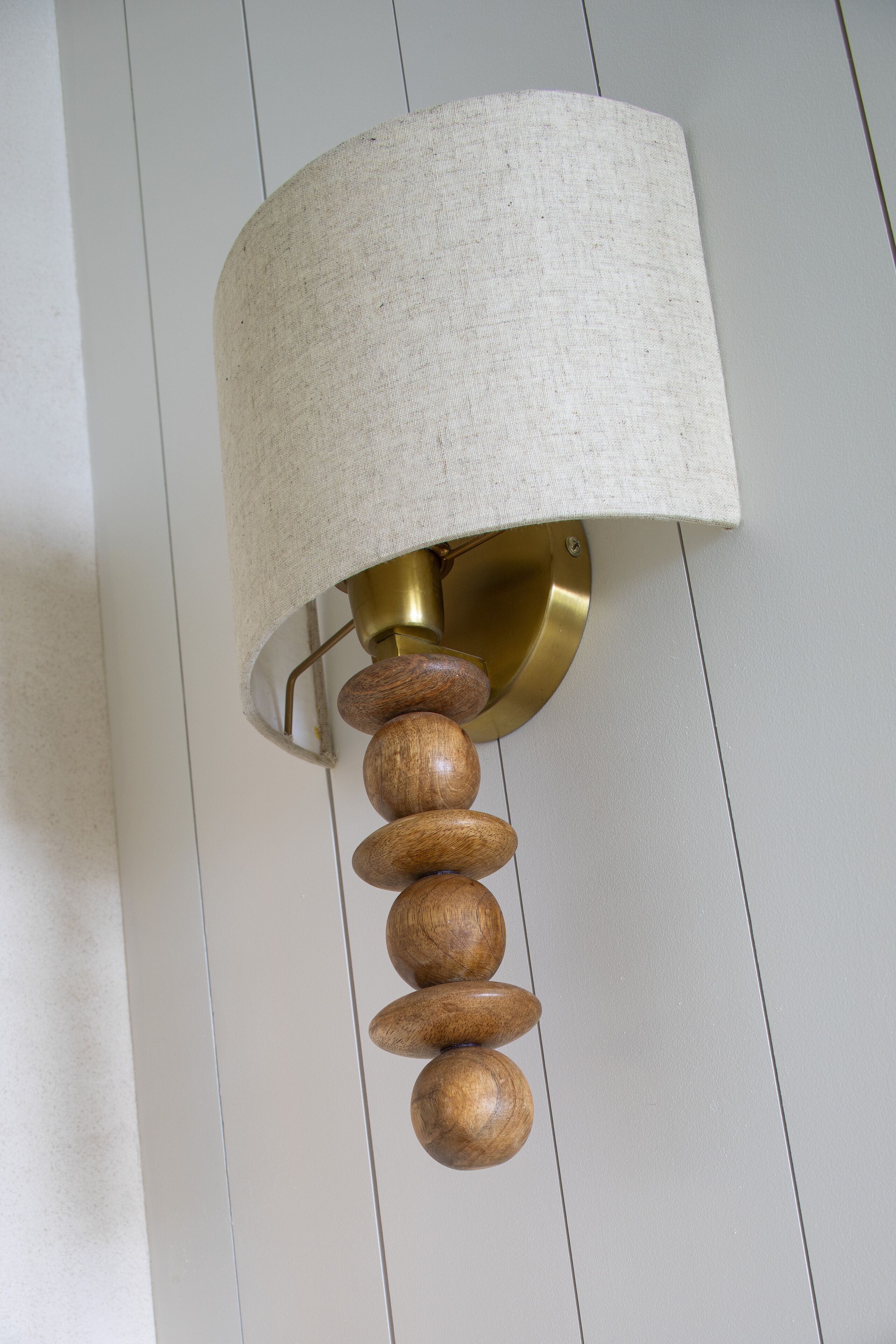 A wall-mounted lamp with a textured lampshade and wooden accents.