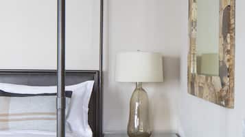 Une chambre à coucher avec un lit à baldaquin, une table de chevet avec une lampe et un miroir au mur.