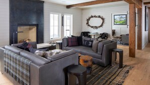 A modern living room with a sectional sofa, a fireplace, and a rustic wooden beam ceiling. - Vaquera House (Crested Butte)