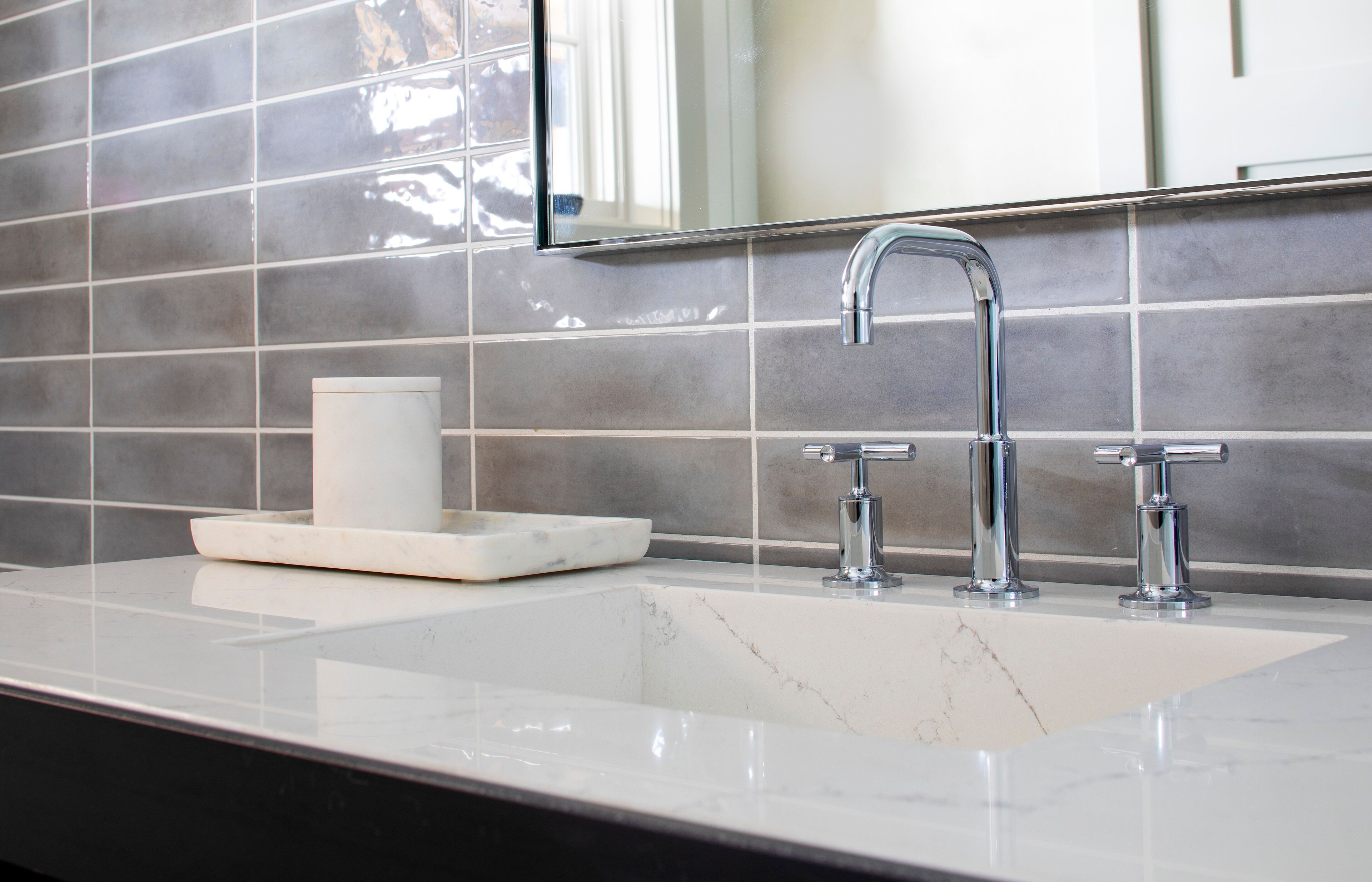 Une salle de bain avec un lavabo blanc, deux robinets chromés et un miroir au-dessus du lavabo.