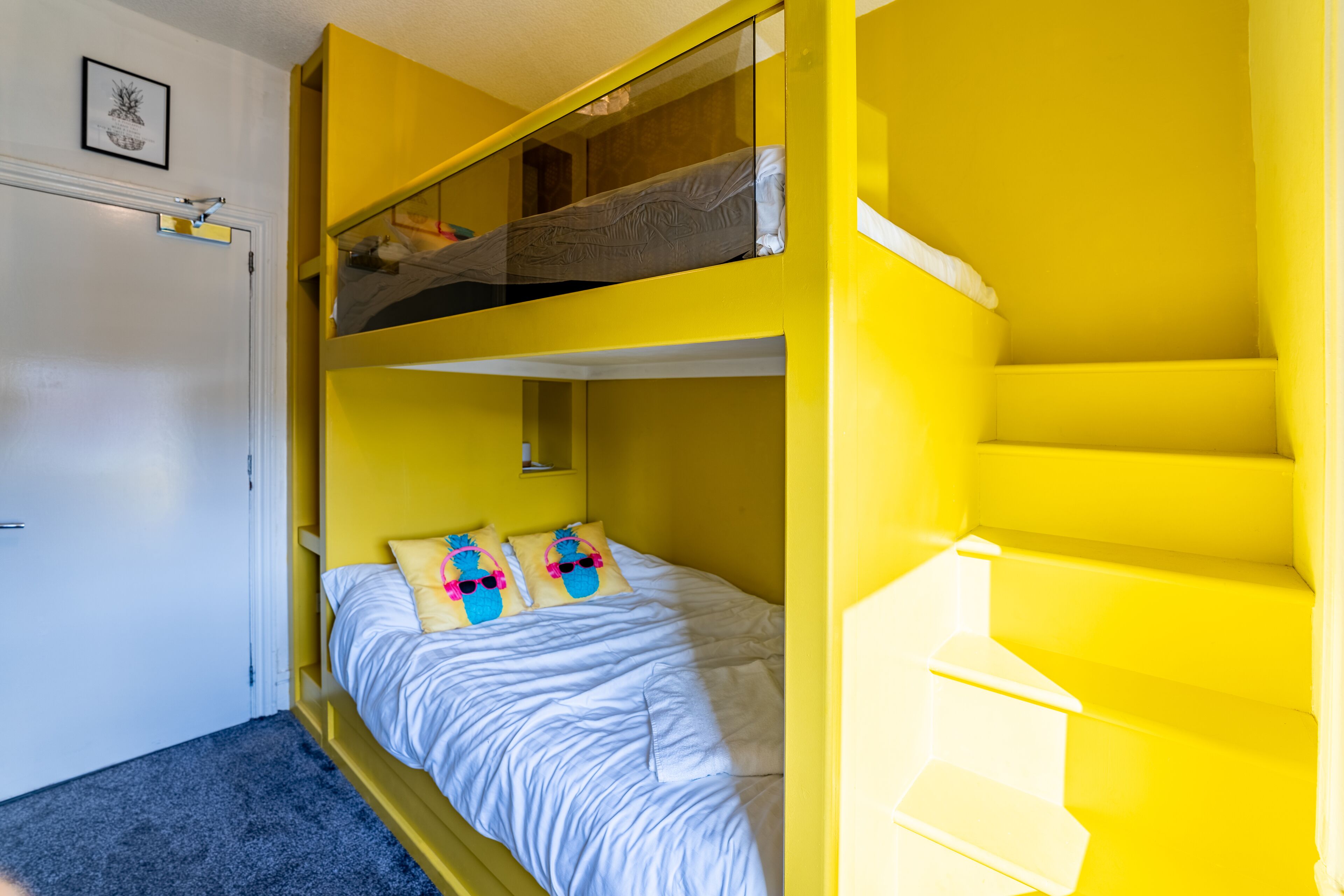 A room with a bunk bed, a single bed, and a staircase.