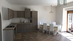 Una cucina moderna con zona pranzo, che include un fornello a gas, mobili bianchi e un tavolo con sedie.