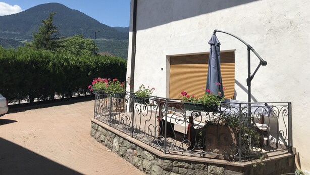 Un edificio con un balcone, una porta in legno e una montagna sullo sfondo.