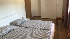 Camera da letto con un'armadiatura in legno, un letto singolo con copriletto decorato e una sedia.