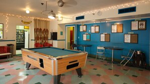 Ein Billardtisch in einem Raum mit blauer Wand und einer Pinnwand mit verschiedenen Aushängen.