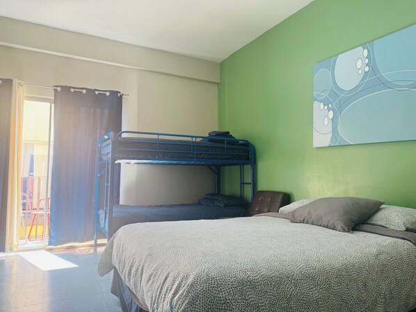 Een kamer met een stapelbed, een enkel bed, een groene wand en een raam met gordijnen.
