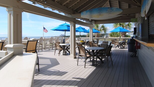 A covered outdoor seating area with tables and chairs, a menu board, and an American flag. - OASIS BEACH RETREAT NORTH MYRTLE BEACH (Myrtle Beach)