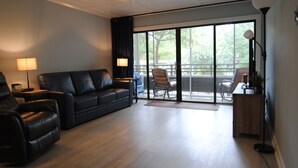 A modern living room with a black leather sofa, a wooden coffee table, and a dining area with a table and chairs. - OASIS BEACH RETREAT NORTH MYRTLE BEACH (Myrtle Beach)