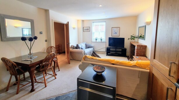 A compact living space with a dining area, a sofa, a TV, and a fireplace. - Charming Mews House in the Heart of Lymington (Lymington)