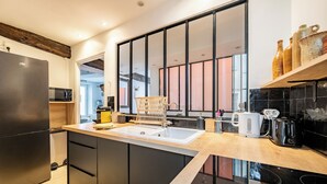 A modern kitchen with a black refrigerator, wooden cabinets, a sink, and a coffee maker.