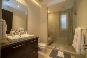A modern bathroom with a glass-enclosed shower, a white sink, and a large mirror. - Los Suenos Resort Montecielo 3E (Jacó)