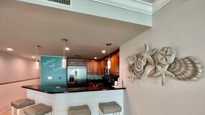 Une cuisine moderne dotée d’un îlot central, de meubles en bois et d’un élément décoratif mural.