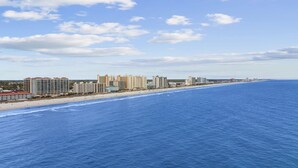 Ein Küstenhotel mit mehreren Hochhäusern, einem Strand und einem wolkenlosen, blauen Himmel.