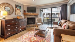 A living room with a fireplace, a sofa, a coffee table, and a TV. - Lodge at Mtn Village A222 | Ski-In/Out | Hot Tub | Plaza View | PCMR | Pool (Park City)