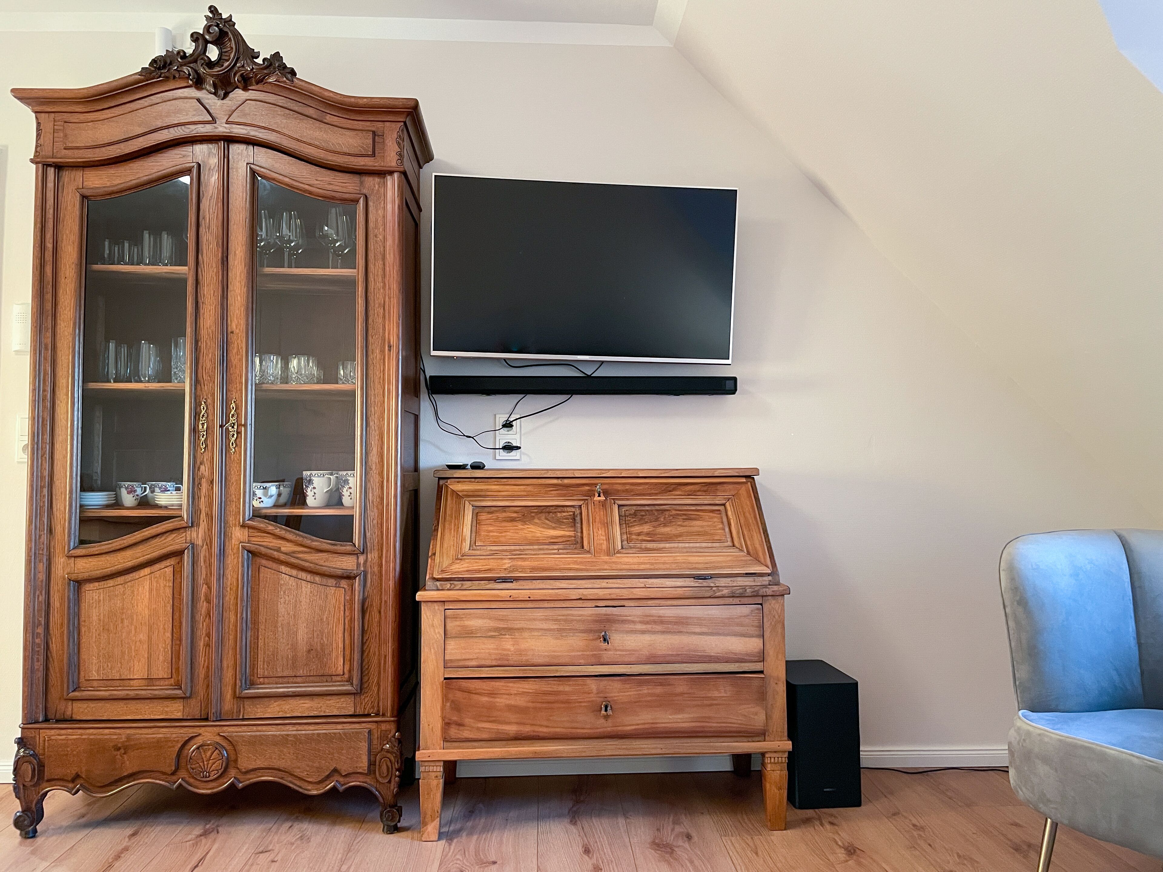 A wooden cabinet with glass doors and a flat-screen TV mounted on the wall.