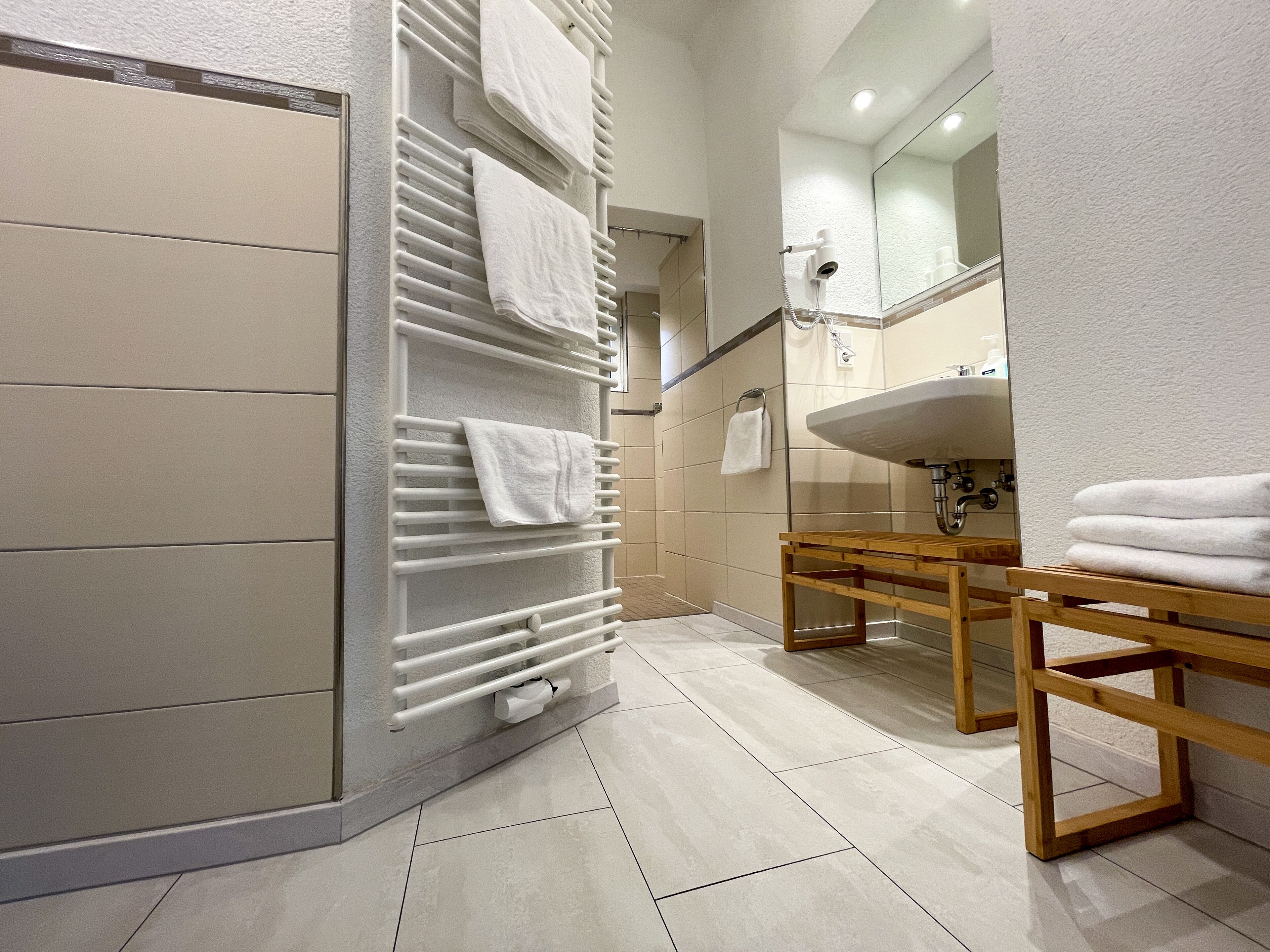 Une salle de bain moderne dotée d’un porte-serviettes intégré, d’un meuble-lavabo en bois et d’un grand miroir au-dessus du lavabo.