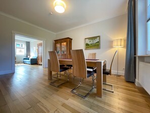 A dining area with a wooden table, four chairs, a cabinet, and a painting on the wall.