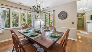 Une salle à manger avec une table en bois, des chaises et un lustre.