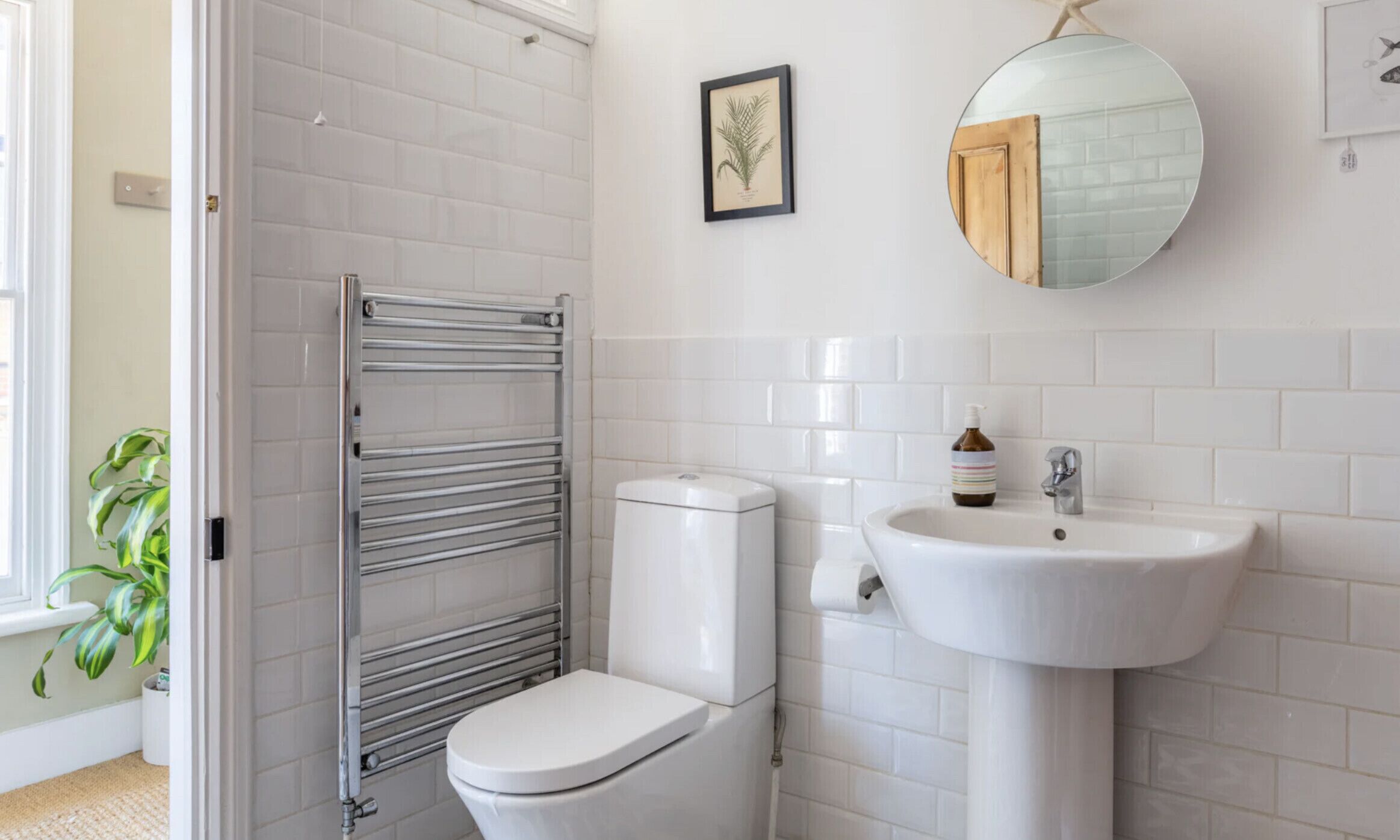 A bathroom with a white toilet, a sink, a towel rack, and a mirror.