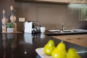 A kitchen with a coffee maker, a sink, and a plate with green pears. - Eagles Nest On Airlie (Airlie Beach)