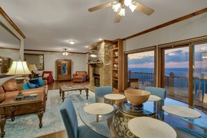 A spacious living room with a fireplace, comfortable seating, and large windows offering a view of the ocean.