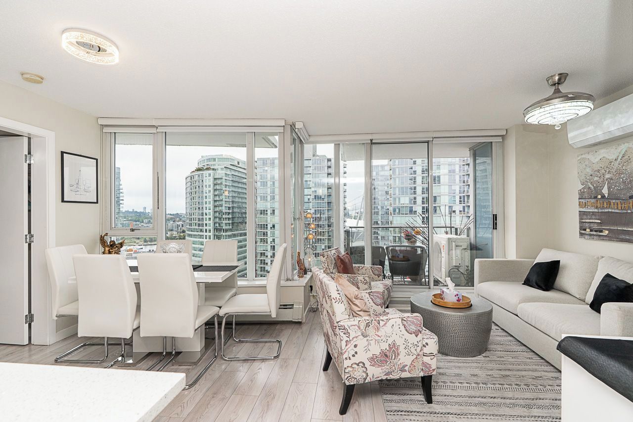 A modern living room with a dining area, large windows, and a city view.
