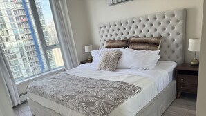 A neatly made bed with a tufted headboard, a patterned throw blanket, and two pillows. - 2BR,2BTR with AC condo in vancouver 6 guests parking (Vancouver)