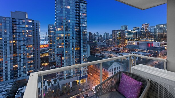 A high-rise building with a balcony overlooking a cityscape at dusk. - 2BR,2BTR with AC condo in vancouver 6 guests parking (Vancouver)