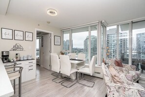 A modern apartment with a dining area, kitchen, and a sofa with a city view.