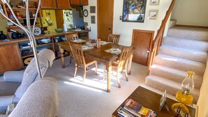 A spacious living area with a dining table, wooden chairs, a sofa, and a coffee table. A staircase is visible in the background. - Cozy Cabin (Silverthorne)