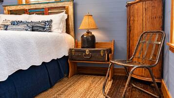 A bedroom with a bed, a lamp, a suitcase, a chair, and a wooden cabinet.