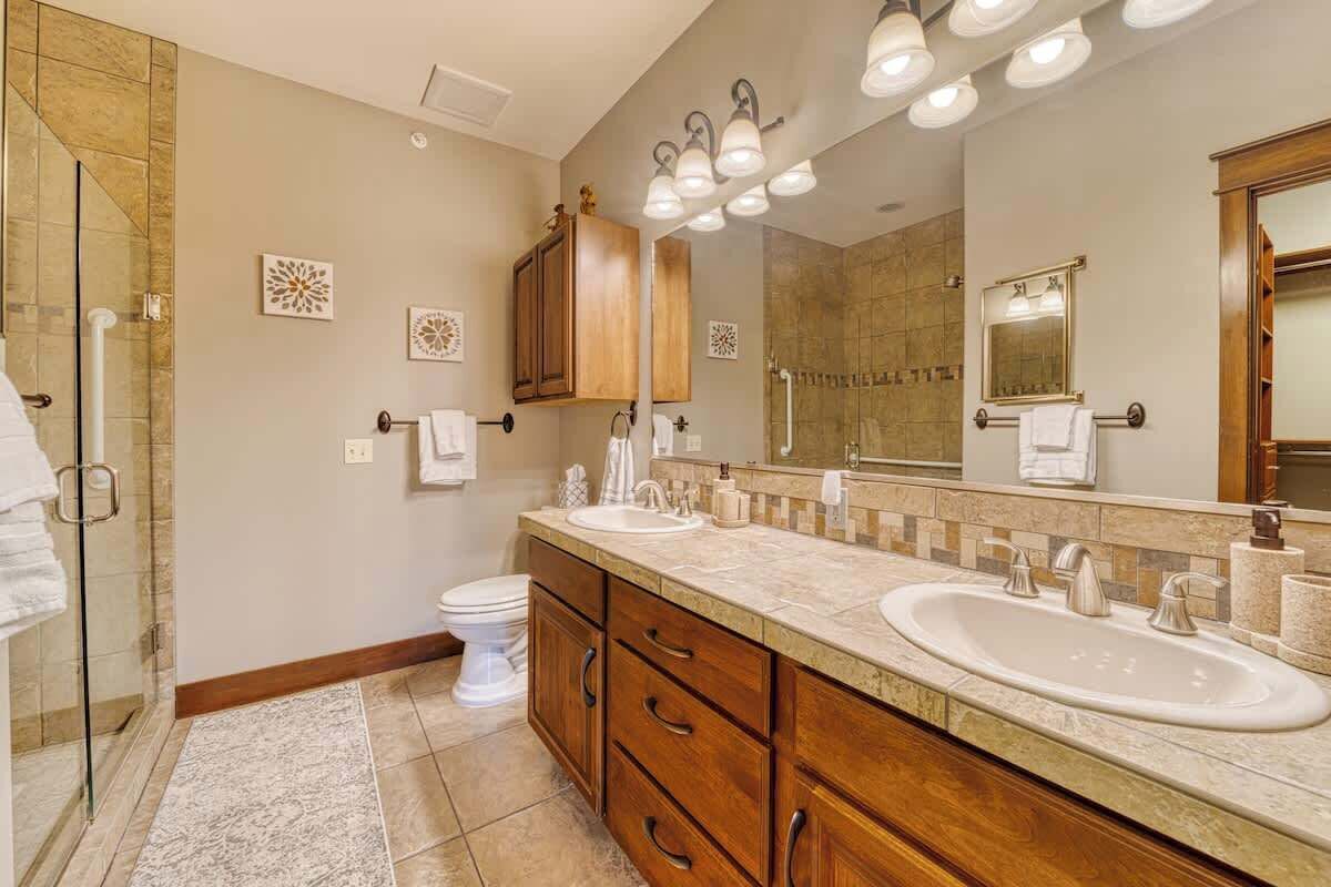 A modern bathroom with two sinks, a shower, and a large mirror.