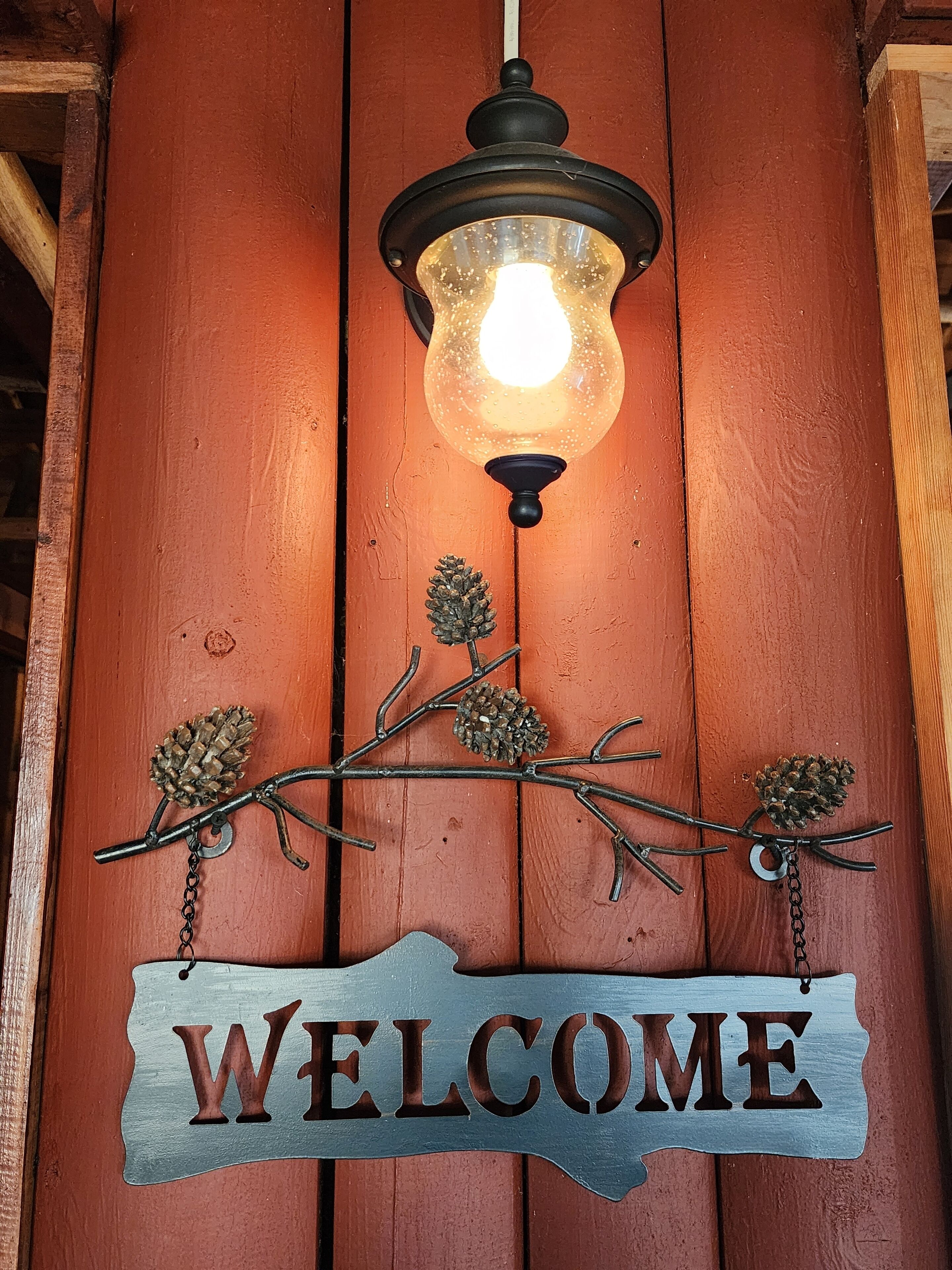 Eine Holzwand mit einem 'WELCOME'-Schild und einer Pendelleuchte.