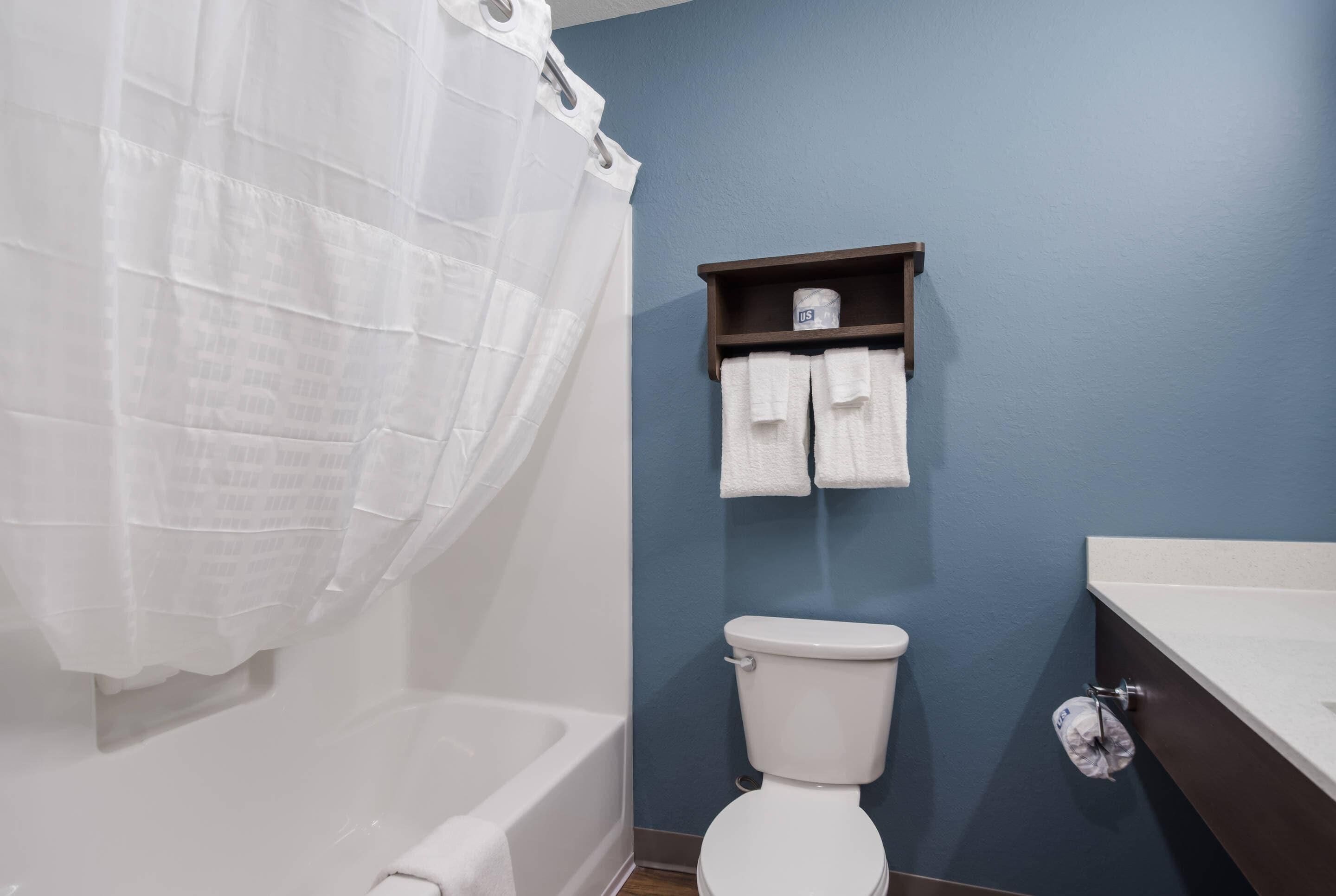 Un baño con una bañera blanca, un inodoro blanco y una pared azul.