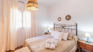 Une chambre à coucher avec un lit, des tables de chevet, un luminaire suspendu et des rideaux.