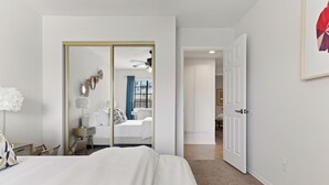 Une chambre d’hôtel moderne équipée d’un grand lit, d’un bureau, d’une chaise, d’un miroir et d’une armoire.
