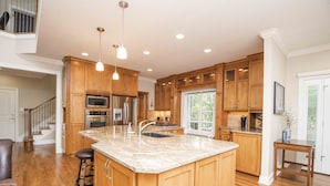 A spacious kitchen with wooden cabinets, a large island, stainless steel appliances, and pendant lighting. - "A Place To Land" on WATTS BAR LAKE with a PRIVATE BOAT DOCK! (Spring City)