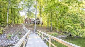 A wooden deck leading to a house surrounded by a forest. - "A Place To Land" on WATTS BAR LAKE with a PRIVATE BOAT DOCK! (Spring City)