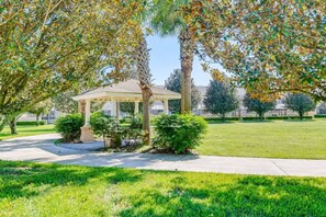 Relax in a serene gazebo surrounded by lush greenery and mature trees.