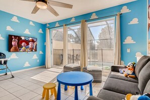 Enjoy a spacious room with a large window, ceiling fan, and comfortable seating area featuring a sofa and stools.
