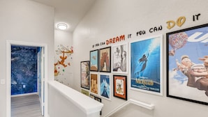A hallway with a staircase, decorated with movie posters and a motivational quote on the wall. - Windsor Hills Resort/3Bed/POOL/Near Disney (Kissimmee)